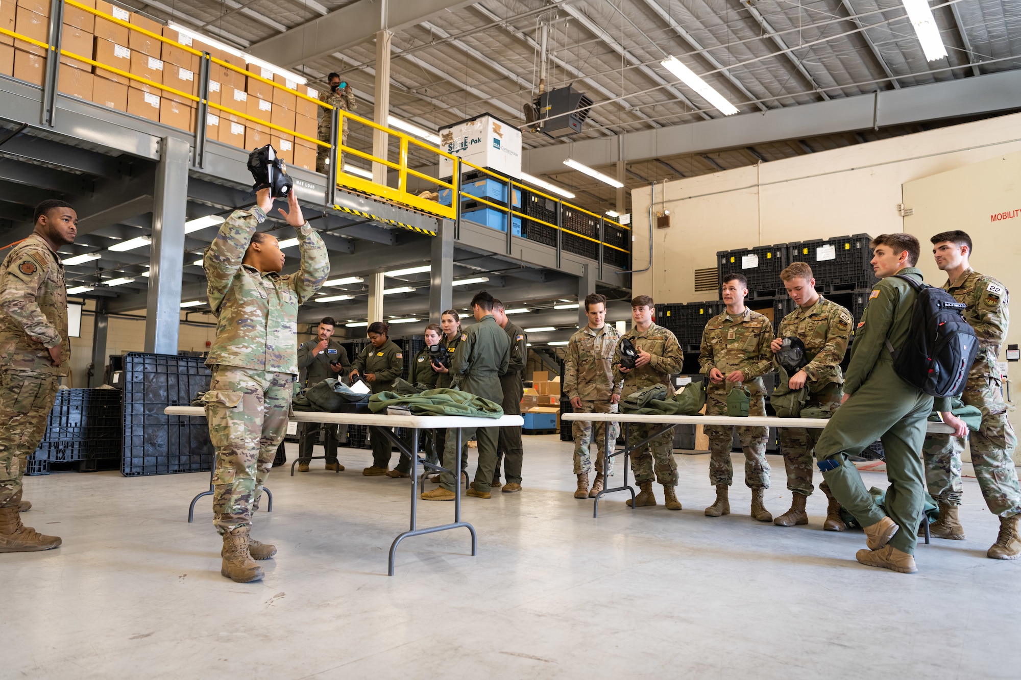 Airmen watch as another Airmen lifts a gas mask over her head.