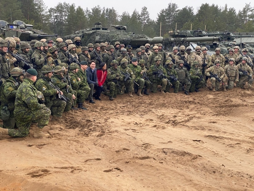 A man and woman pose for a photo with military personnel.