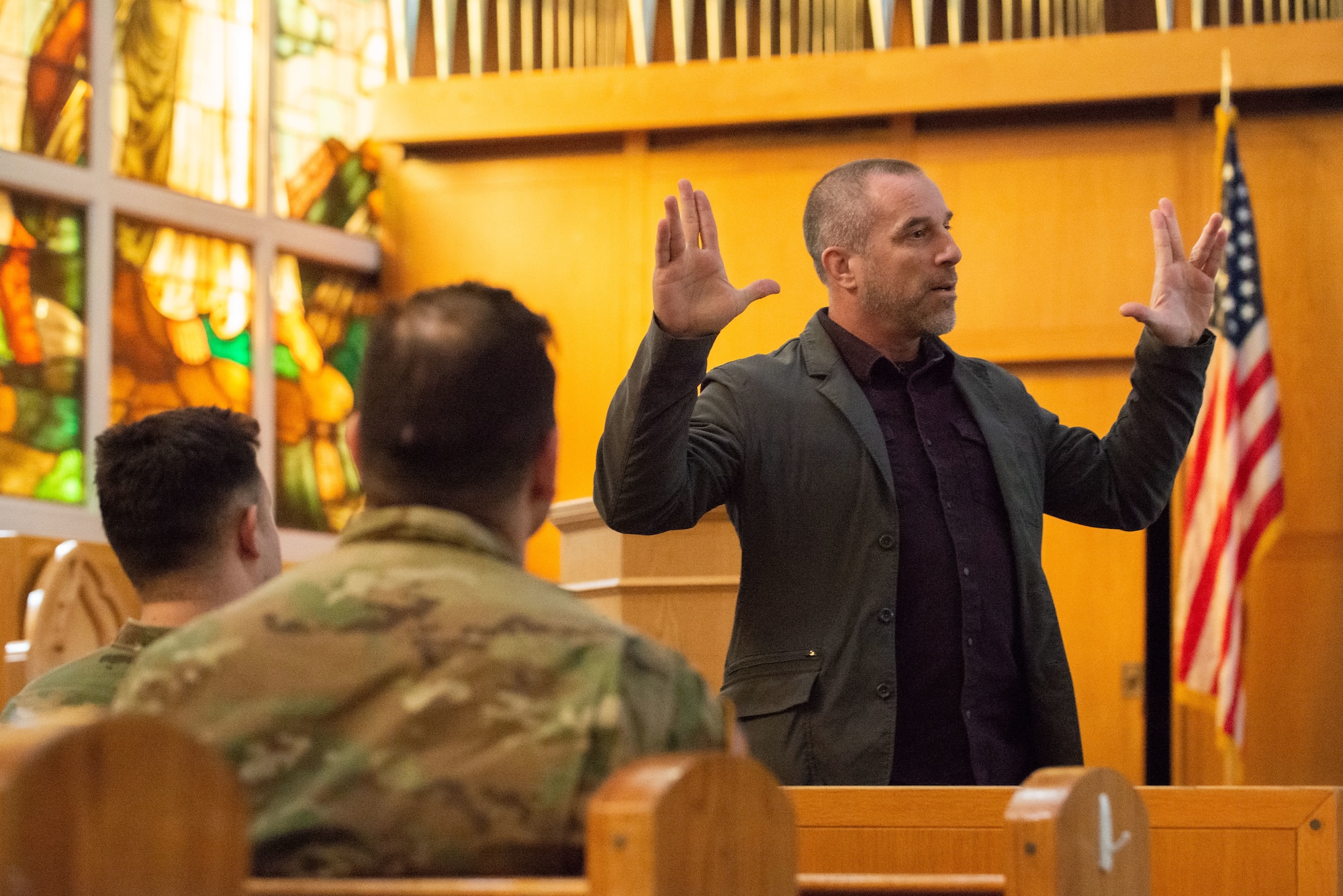 A photo of a man speaking in front of a group of soldiers