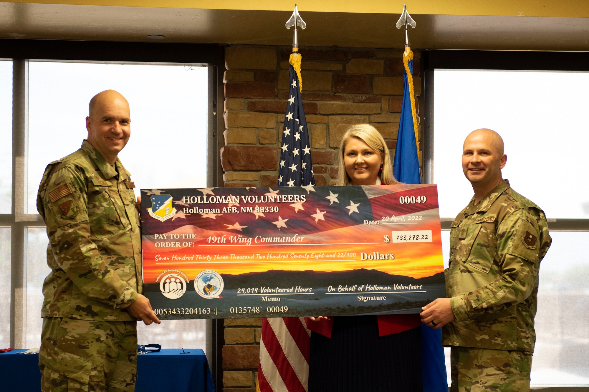 Col. Ryan Keeney 49th Wing commander, Chief Master Sgt. Thomas Temple, 49th Wing command chief and Julie Franklin, Airman & Family Readiness Center flight chief, pose together with a check for 733,278.22 dollars during a volunteer awards ceremony in Club Holloman April 20, 2022, on Holloman Air Force Base, New Mexico. The check represents the total value of dollars raised for all the volunteer hours for this year. (U.S. Air Force photo by Airman Isaiah Pedrazzini)