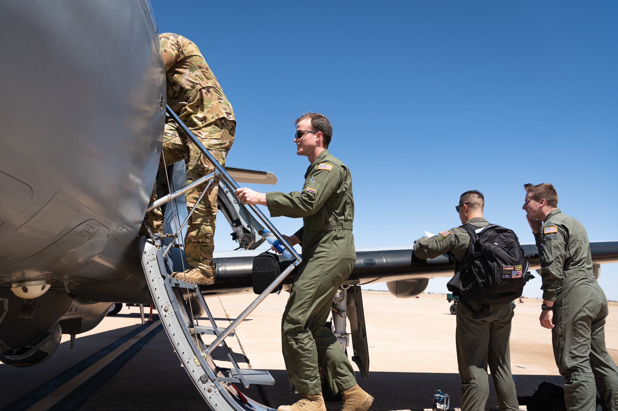 Two Airmen climb into a small plane while two other Airmen look at the plane's wing