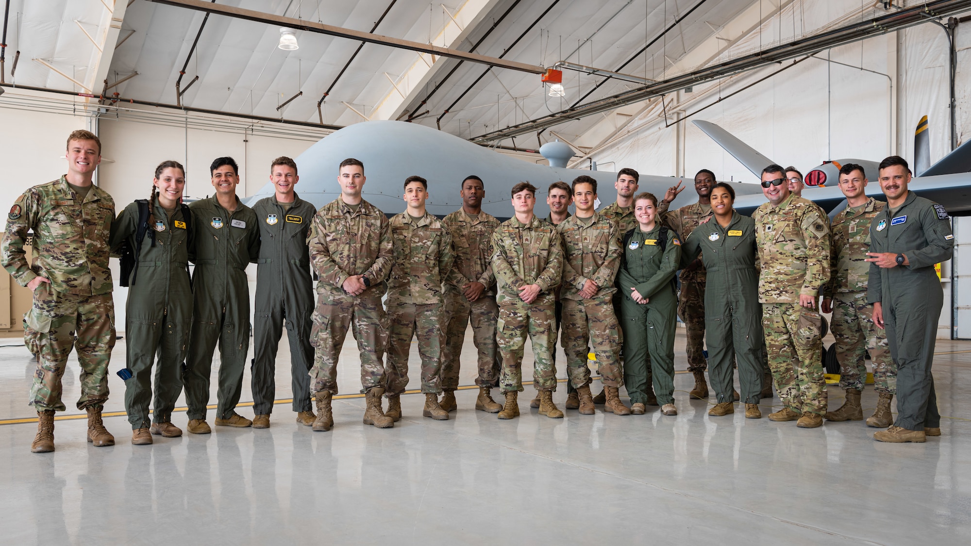Airmen pose for a group photo in front of a remotely piloted drone aircraft.
