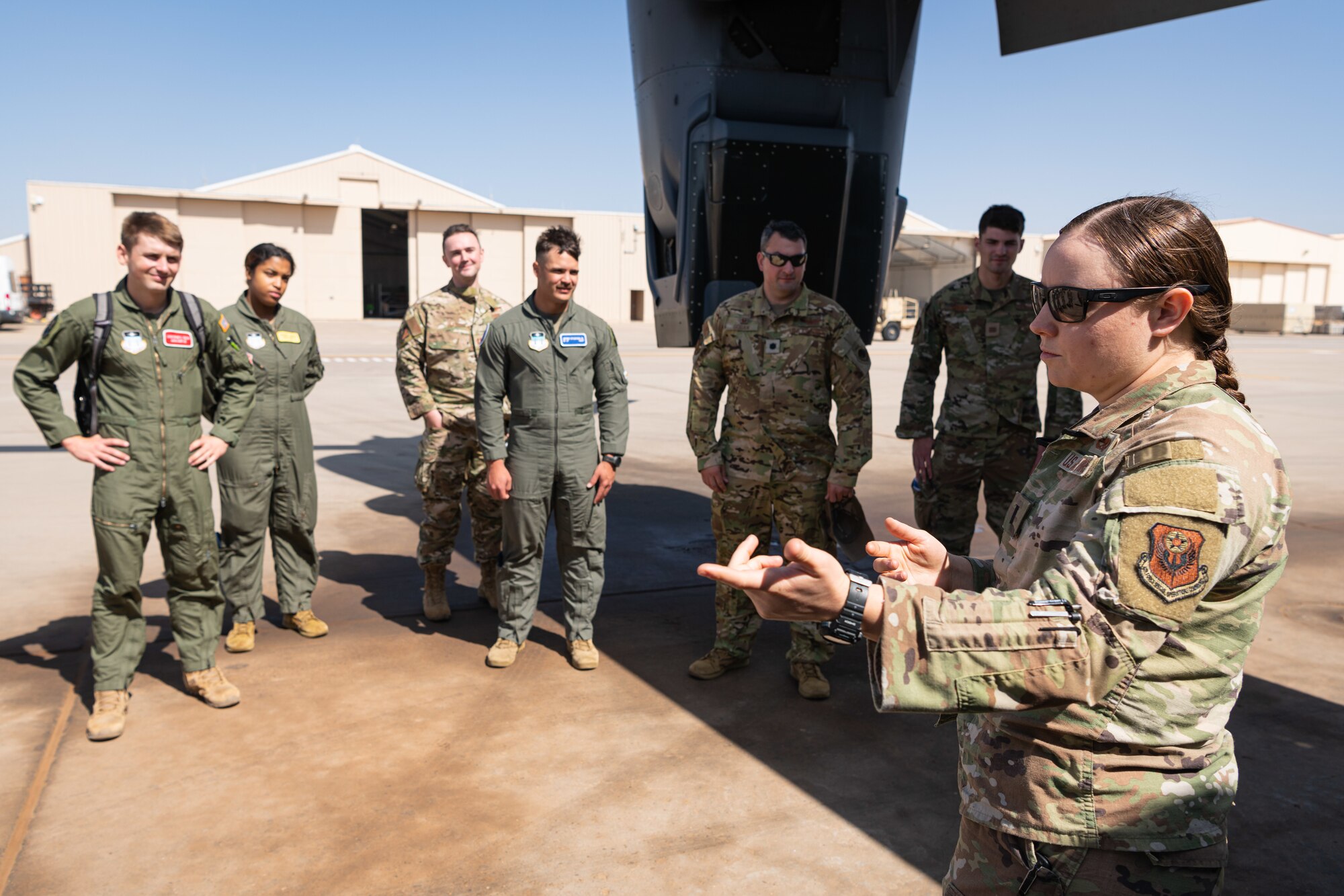 Airmen surround an Air Force officer giving a briefing on a flight line.