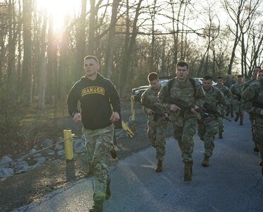 (Left) Staff Sgt. Paul Almquist, an Ranger and Sapper Assessment Program instructor assigned to Pennsylvania Joint Force Headquarters, leads the participants in a run to the Marquette Lake for the Combat Water Survival Test on April 22, 2022. The CWST is one of several events that challenged the participants physically and mentally to see if they are prepared for Ranger and Sapper School.