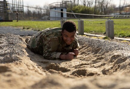 A Soldier low crawls beneath barbed wire during the obstacle course portion of the Ranger and Sapper Assessment Program on April 22, 2022. The weaver, high wall, and more, obstacles challenged the service members during this portion of RSAP.