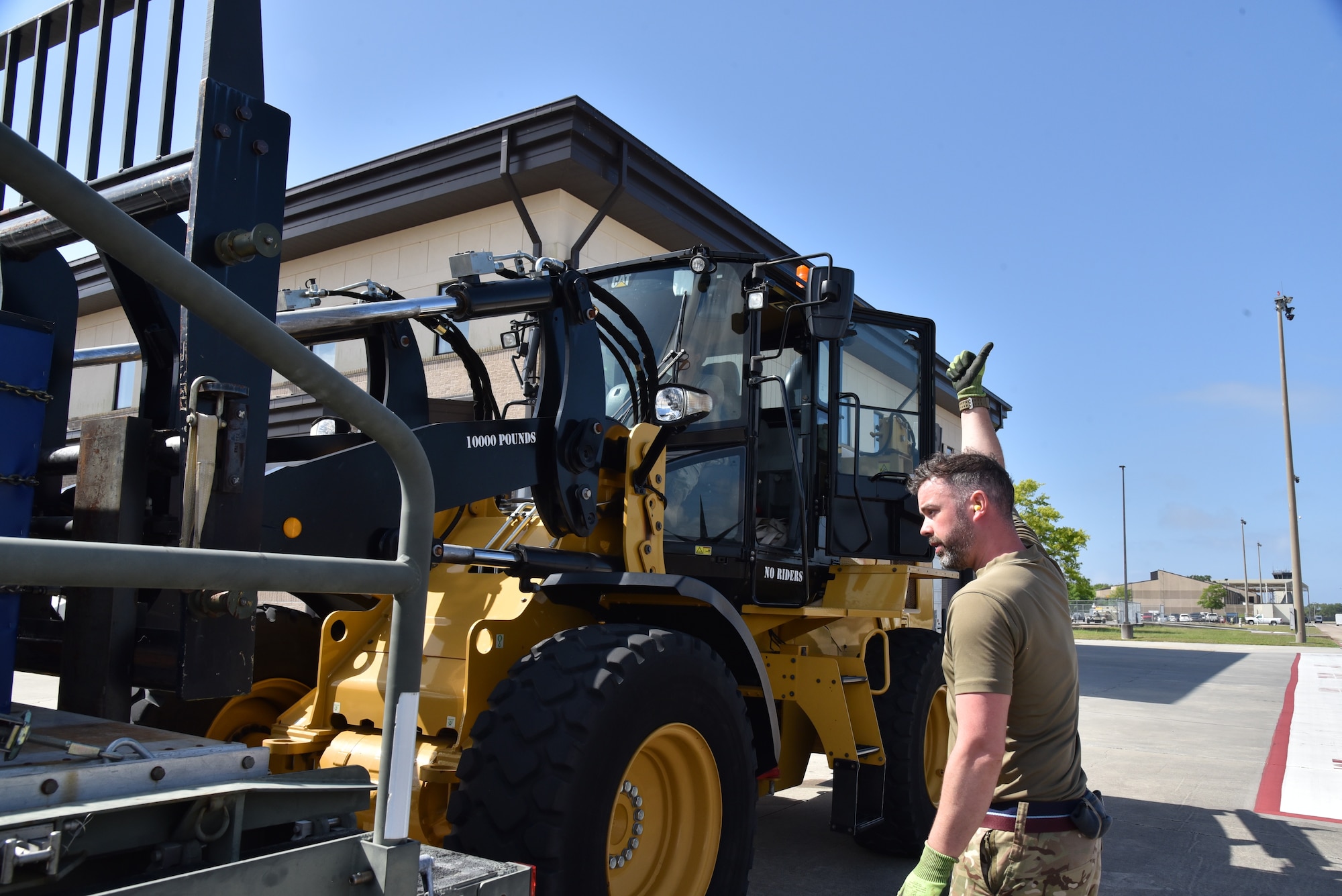 British Royal Air Force Reserve member marshals the driver of the all terrain 10K forklift, directing the removal of a pallet from a K-loader.