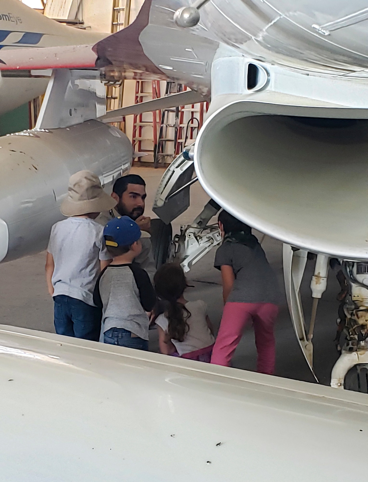 Children seen here are interacting with Flight Test Museum restoration curator, Sergio Cuevas, on the  prototype F-16B at the museum’s restoration Hangar on Edwards AFB. Photo by Renee Marchiano.