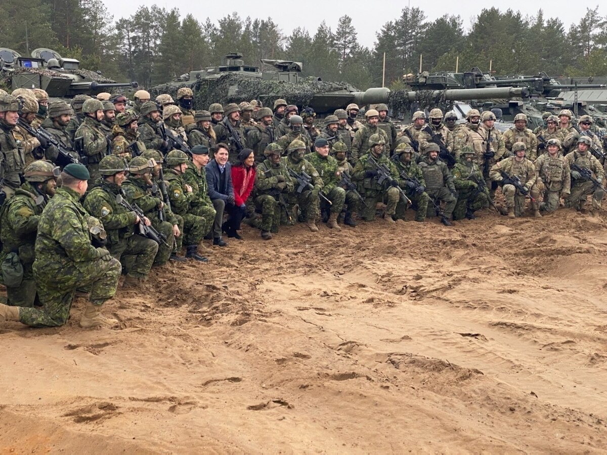 A man and woman pose for a photo with military personnel.