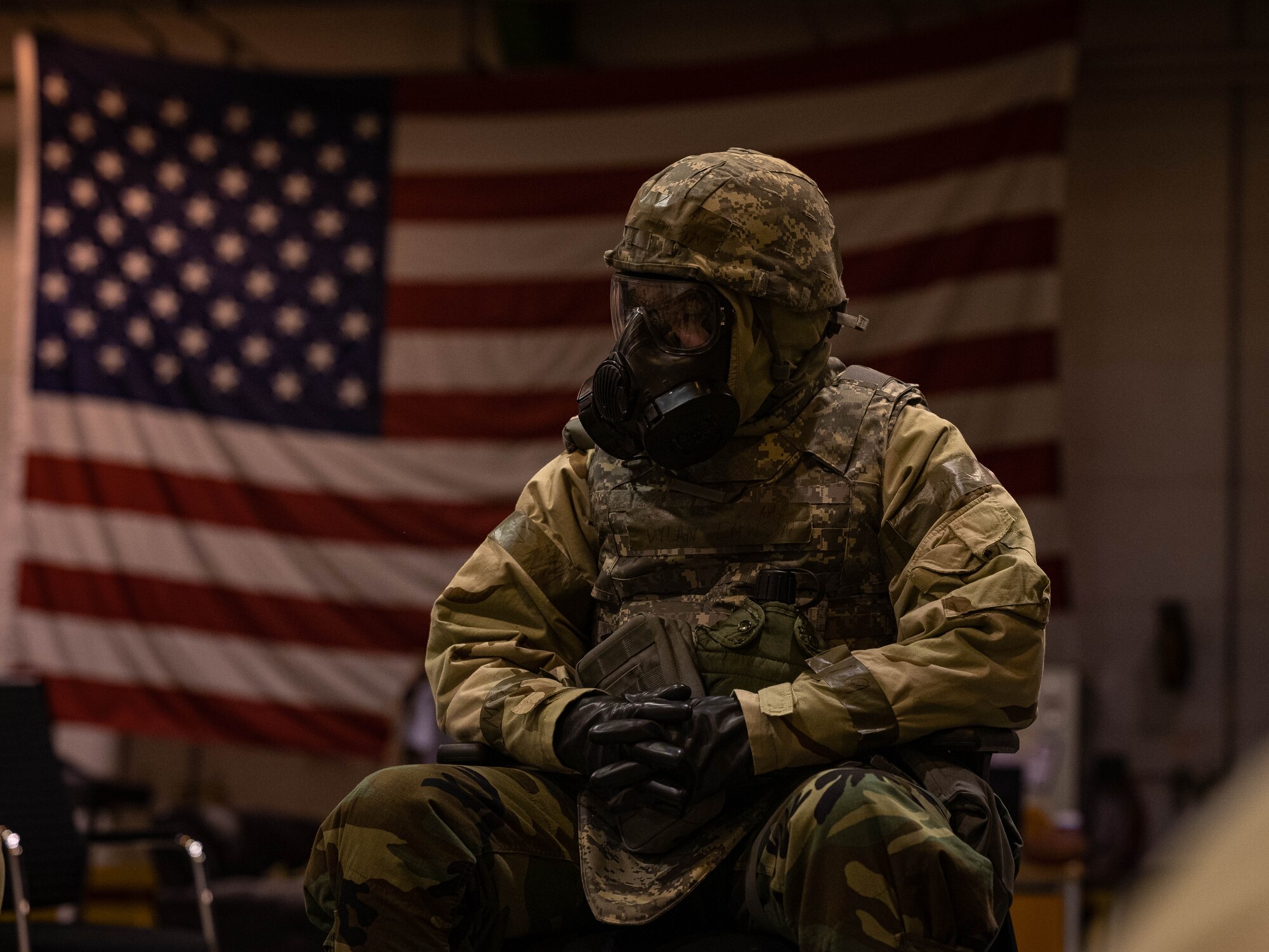 Airman sits in front of flag.