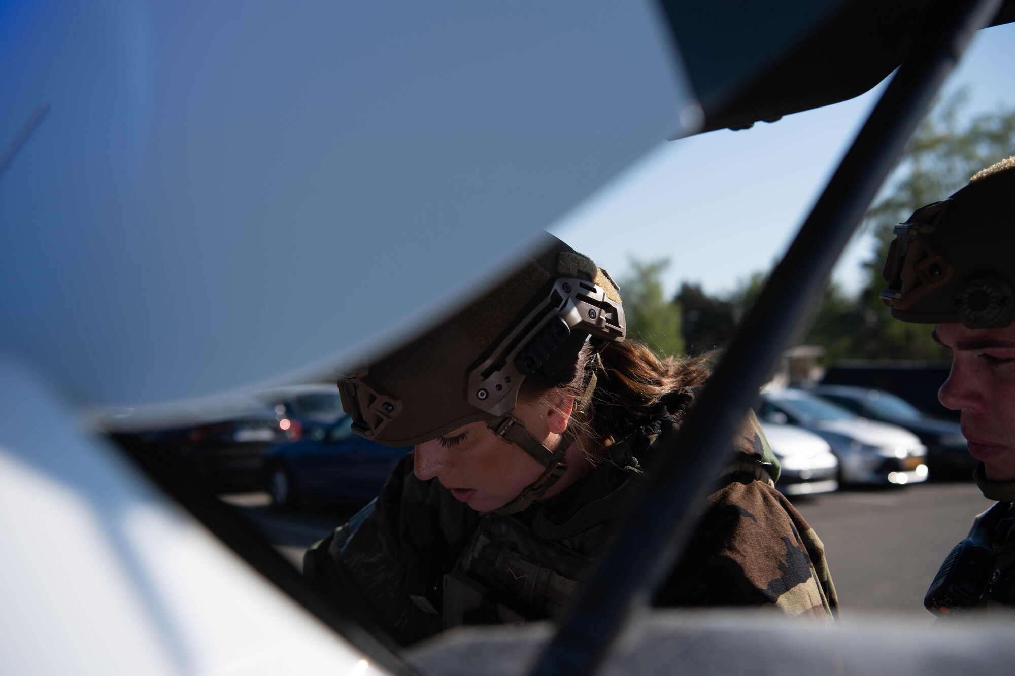 Airmen look into car trunk.