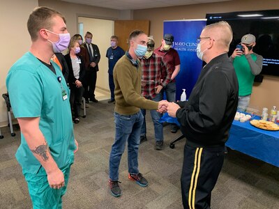 Brig. Gen. Tim Covington, the Wisconsin National Guard’s deputy adjutant general for civil support, presents a coin to 2nd Lt. Jonathon Jennings for his leadership as a platoon leader of Wisconsin National Guard nursing assistants supporting health care facilities during a ceremony at the Mayo Clinic in La Crosse April 26, 2022. The Wisconsin National Guard is winding down its nursing assistant support mission around the state.