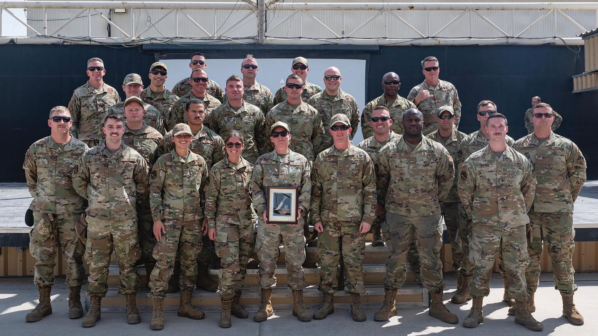 Airmen from the 87th Aerial Port Squadron pose with their award for 380th Air Expeditionary Wing team of the quarter at Al Dhafra Air Base, April 8, 2022. While assigned to the air transportation function in the 380th Expeditionary Logistics Readiness Squadron, the 29 Airmen worked 12-hour shifts, six days per week, coordinating cargo movement, passenger procedures, joint training exercises and more. (Courtesy photo)