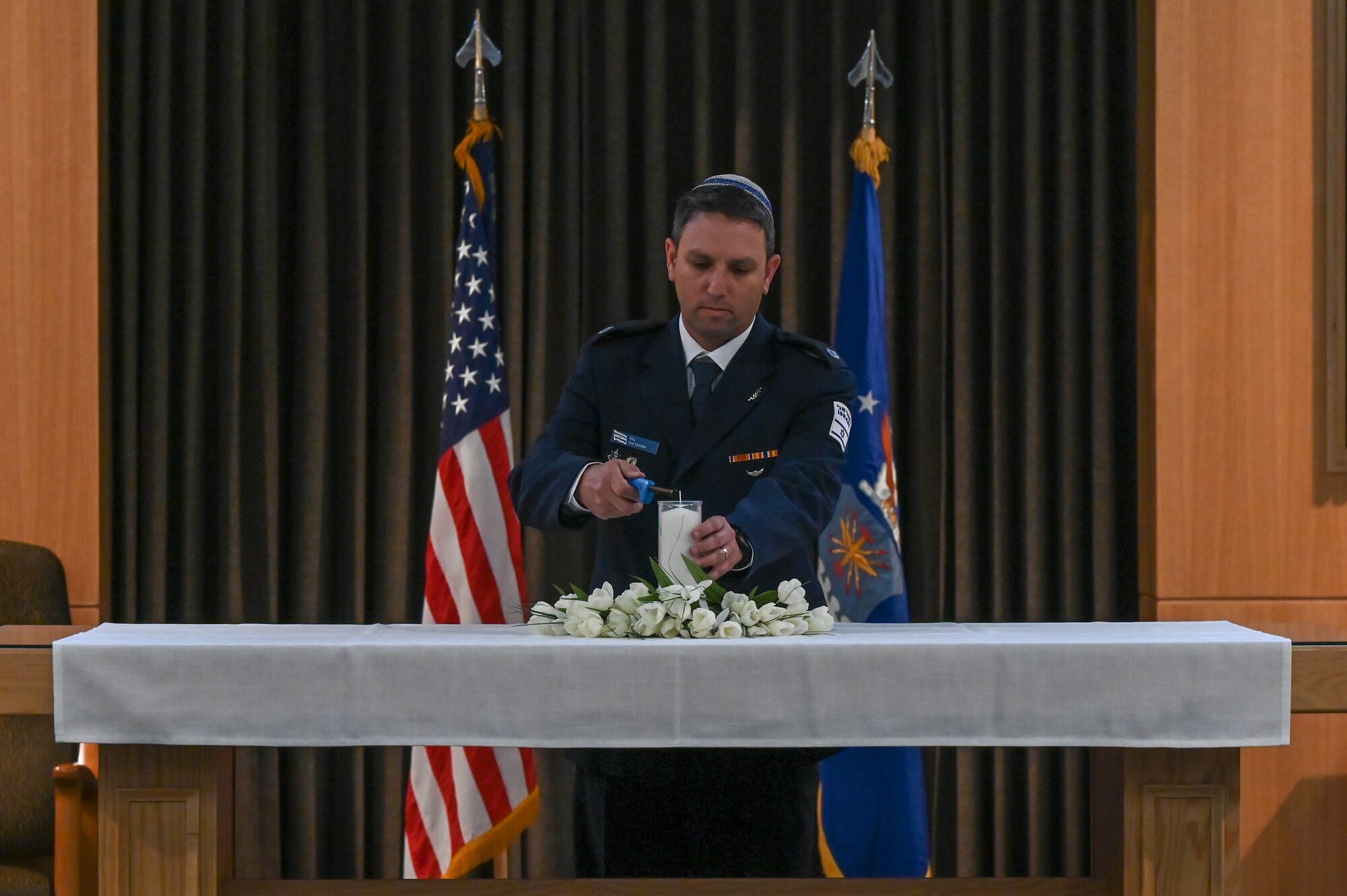 Major Guy Gombo lights a candle on a table.