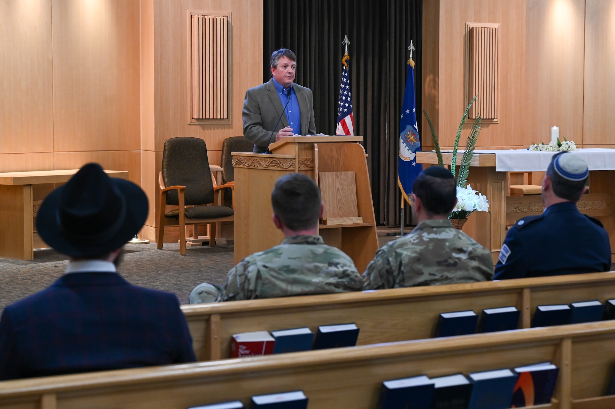 Mike Moore speaks at a podium in front of an audience seated in pews.