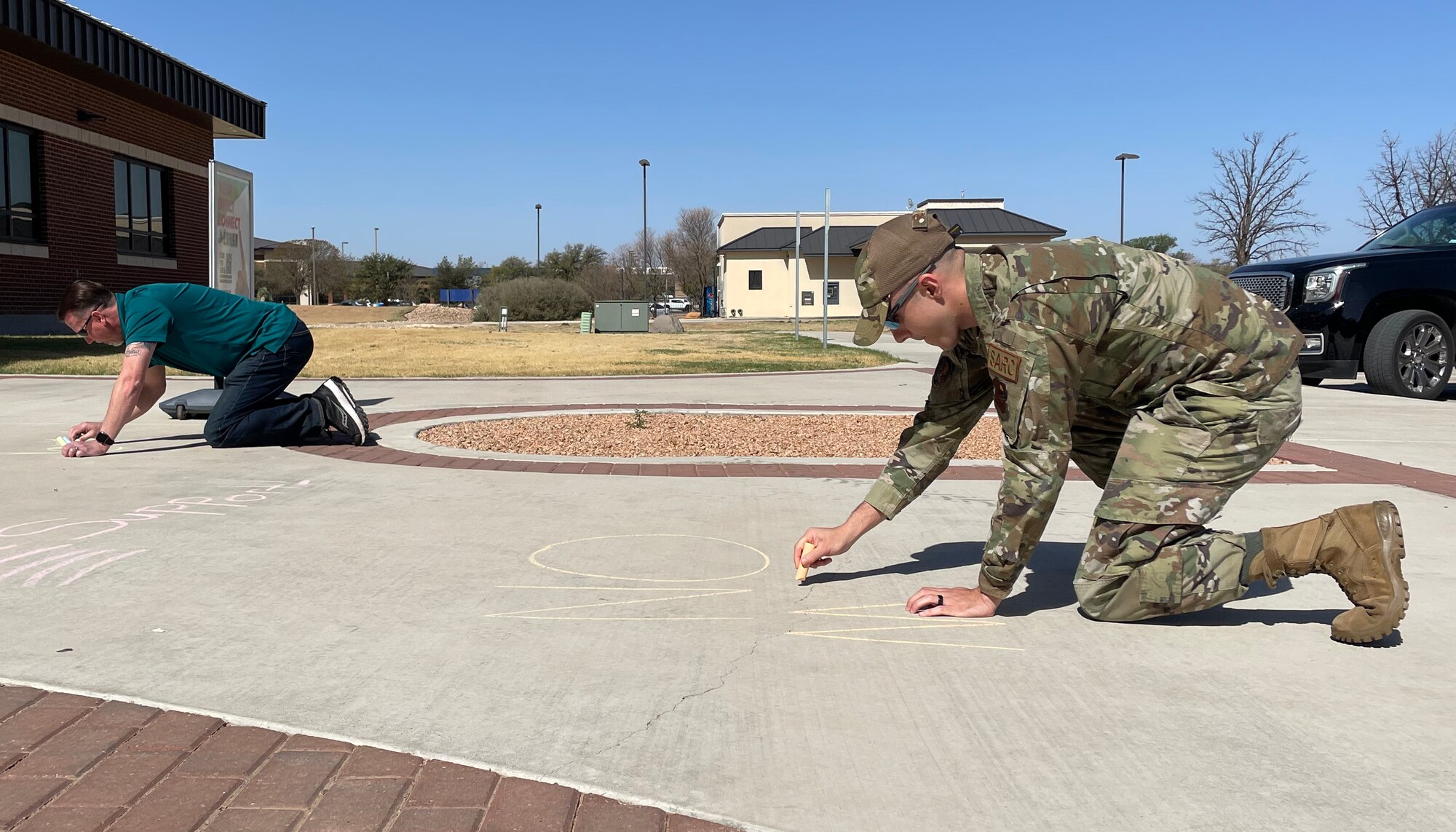 U.S. Air Force Tech. Sgt. Gage Tressitt, 17th Training Wing deputy sexual assault response coordinator, ‘chalks the walk’ at Goodfellow Air Force Base, Texas, April 8, 2022. Tressitt wrote messages about sexaul assault on the sidewalk in a SAPR awareness campaign.(U.S. Air Force photo by Senior Airman Abbey Rieves)