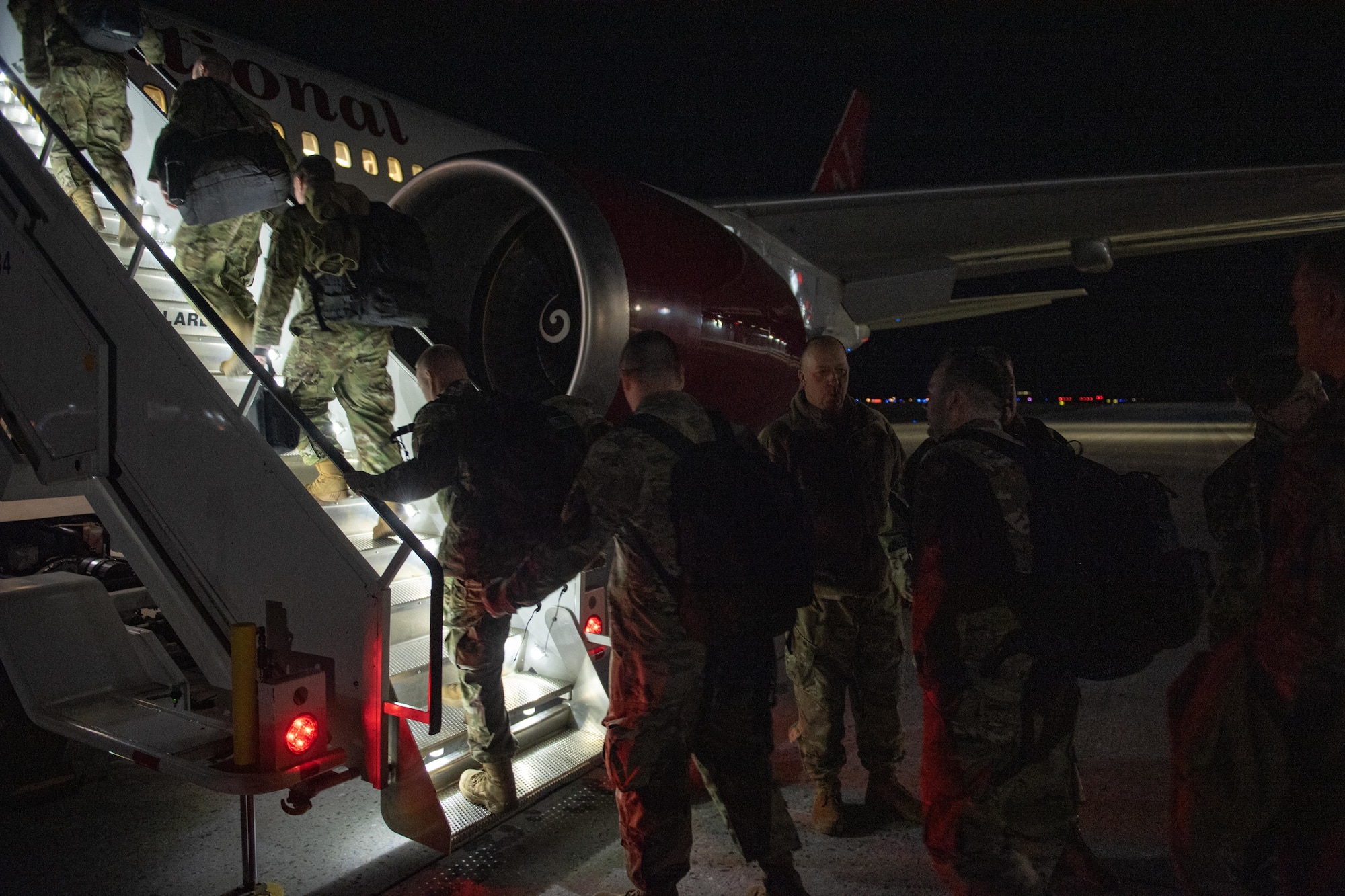 Photo of Airmen from the Vermont Air National Guard boarding a plane for a deployment to Europe near midnight from the Vermont Air National Guard Base, South Burlington, Vermont, April 29, 2022.
