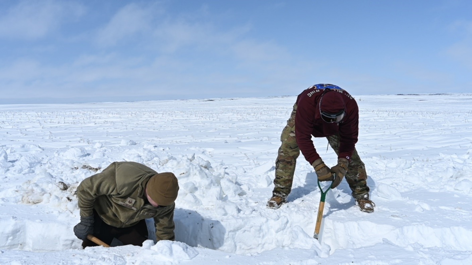 Airmen dig a trench April 26, 2022 at Minot Air Force Base, North Dakota. They shoveled over two feet of snow to prepare for the possible flooding from the melting snow. (U.S. Air Force photo by Senior Airman Caleb Kimmell)