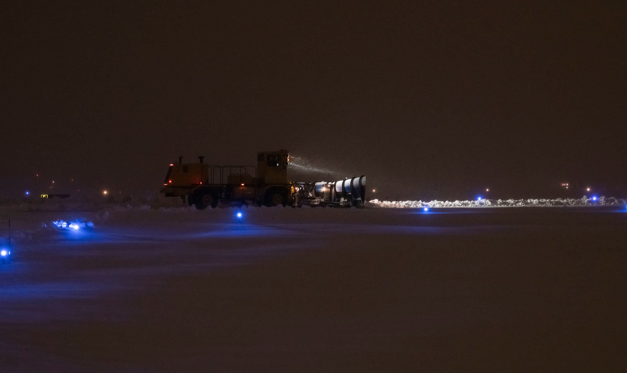 A snow plow drives on the flight line