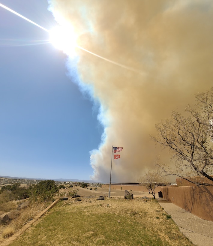 Smoke from the Cerro Pelado Fire, northwest of Cochiti Lake, N.M., is seen behind the Visitor Center flagpole, April 29, 2022.