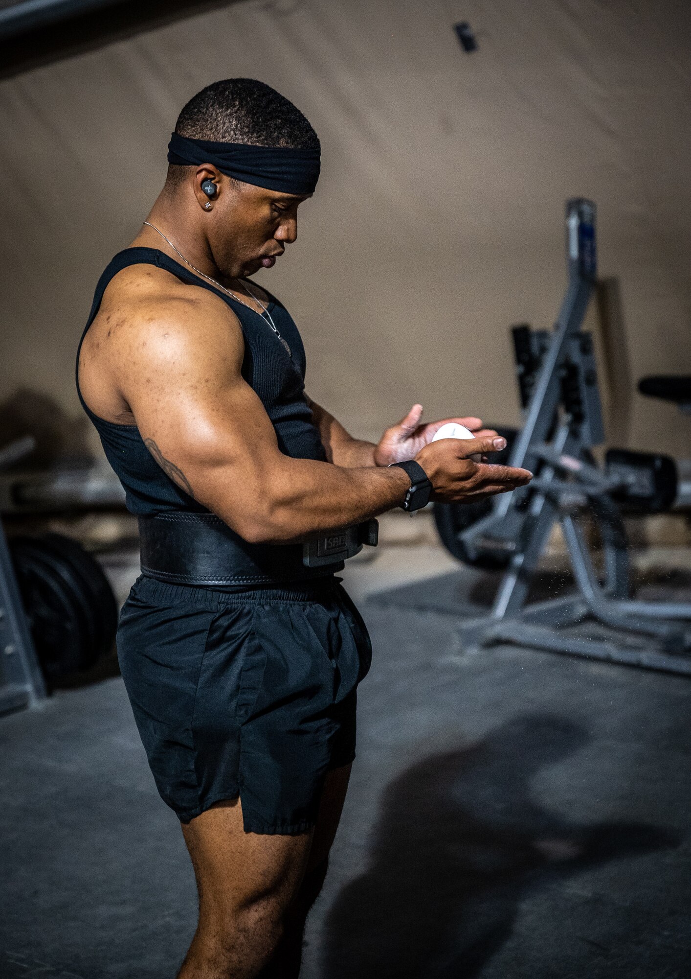 1st Lt.  Anthony Bilal, 332d Expeditionary Contracting Squadron contracting officer, and construction flight commander, chalks up his hands as he prepares to deadlift 535 pounds, as part of his powerlifting training routine, inside the Legends Fitness Center at an undisclosed location in Southwest Asia, April 24, 2022. Bilal recently won a powerlifting competition that included the deadlift, back squat, and bench press. (U.S. Air Force photo by Master Sgt. Christopher Parr)