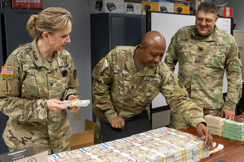 Col. Paige M. Jennings, U.S. Army Financial Management Command commander, and Command Sgt. Maj. Kenneth F. Law, USAFMCOM senior enlisted advisor, inspect new Operational Training Team training currency as Lt. Col. Wayne Hirt, USAFMCOM OST director, looks on at the Maj. Gen. Emmett J. Bean Federal Center in Indianapolis April 8, 2022. The OST provides subject matter expertise and support to finance and comptroller units throughout their entire deployment cycle and evaluates their ability to meet their standards for training proficiency and prepare for multi-domain operations during large-scale combat operations. (U.S. Army photo by Mark R. W. Orders-Woempner)