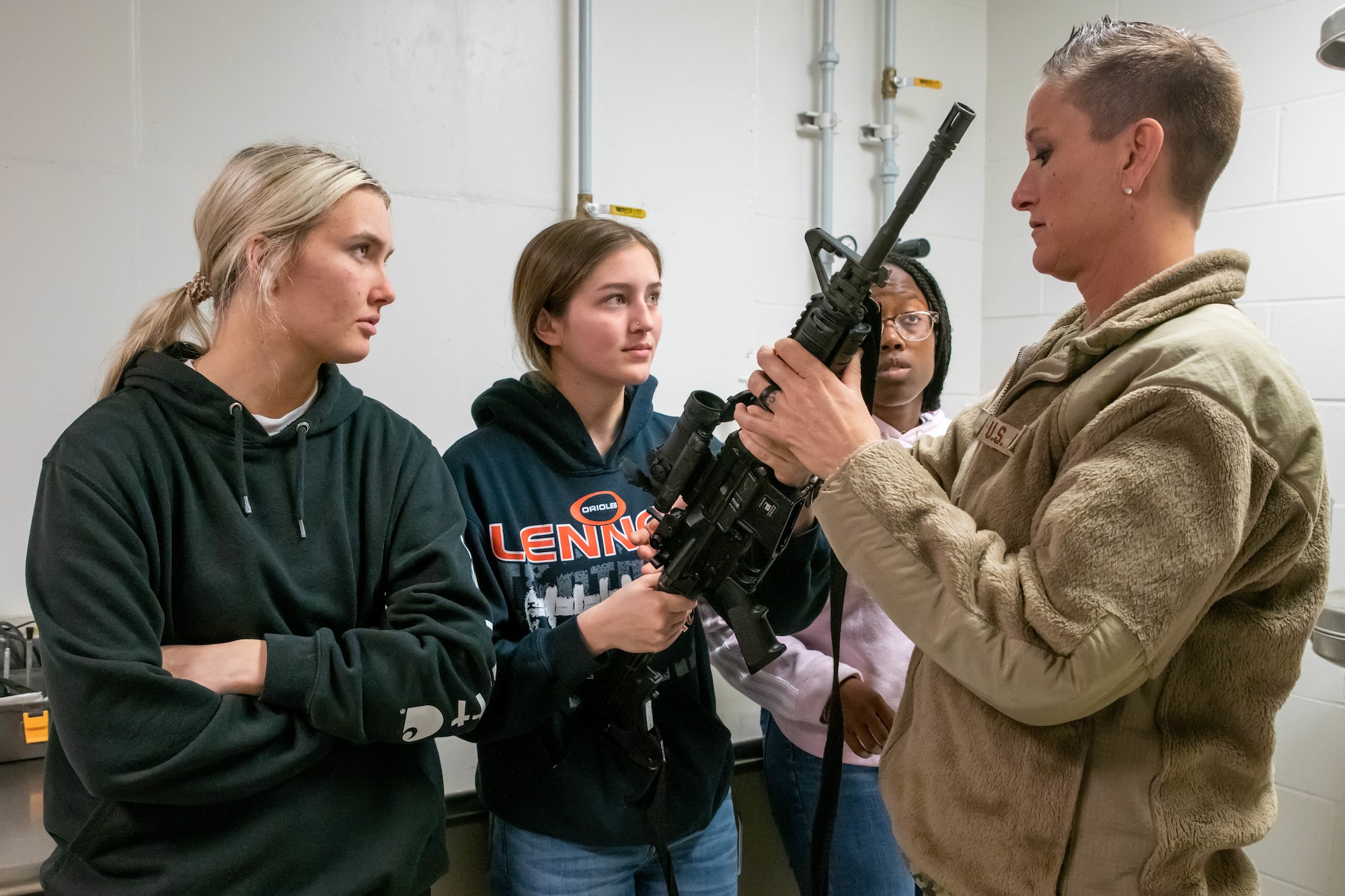 South Dakota Air National Guard Master Sgt. Mandy Jongeward, security forces flight sergeant, 114th Fighter Wing, identifies parts of the M4 carbine for student flight members Ellie Anderson, left, Ellen Boomgarden, center, and Ether Christion, right, during a weapons familiarization training at Joe Foss Field, April 30, 2022.