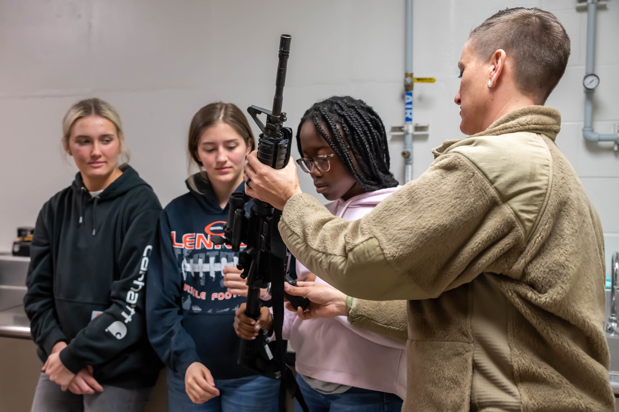 South Dakota Air National Guard Master Sgt. Mandy Jongeward, security forces flight sergeant, 114th Fighter Wing, identifies parts of the M4 carbine for student flight members Ellie Anderson, left, Ellen Boomgarden, center, and Ether Christion, right, during a weapons familiarization training at Joe Foss Field, April 30, 2022.