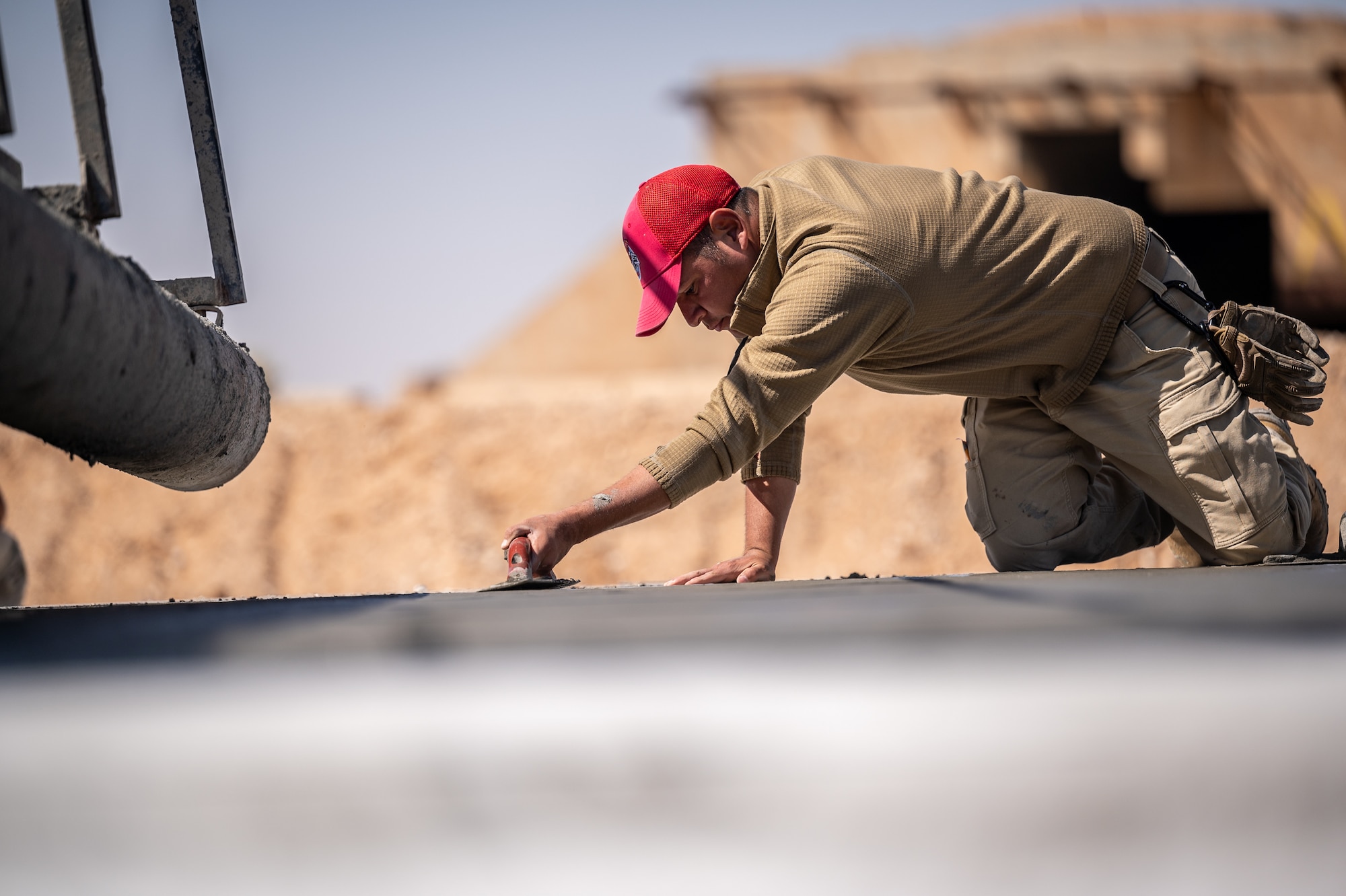 Staff Sgt. Manuel Acuna, 1st Expeditionary Civil Engineer Group pavements and construction equipment operator craftsman, floats and edges concrete to fix imperfections during a runway overrun repair project at an undisclosed location in Southwest Asia, April 14, 2022. (U.S. Air Force photo by Master Sgt. Christopher Parr)