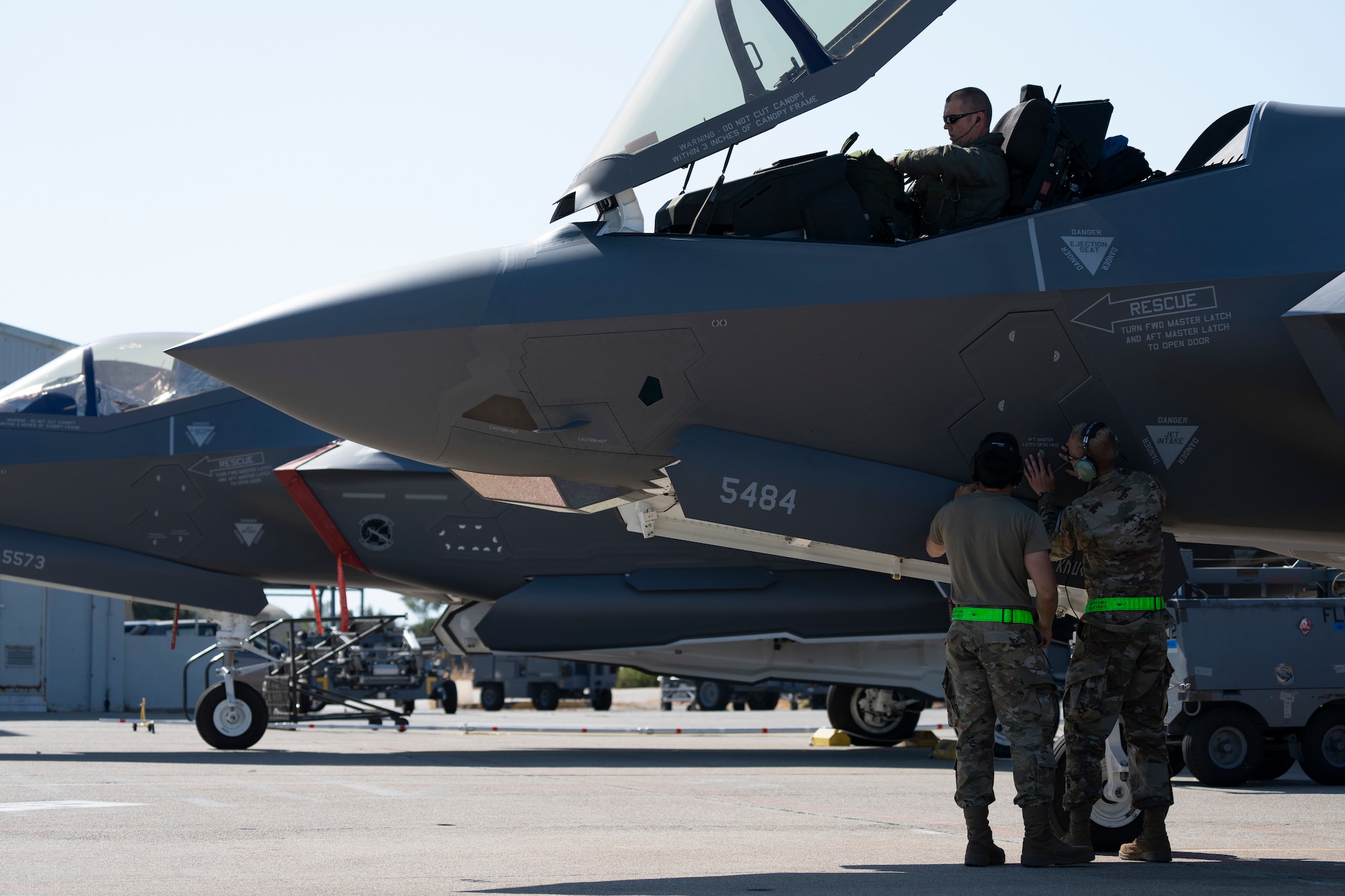 Photo of two Airmen standing next to a fighter jet