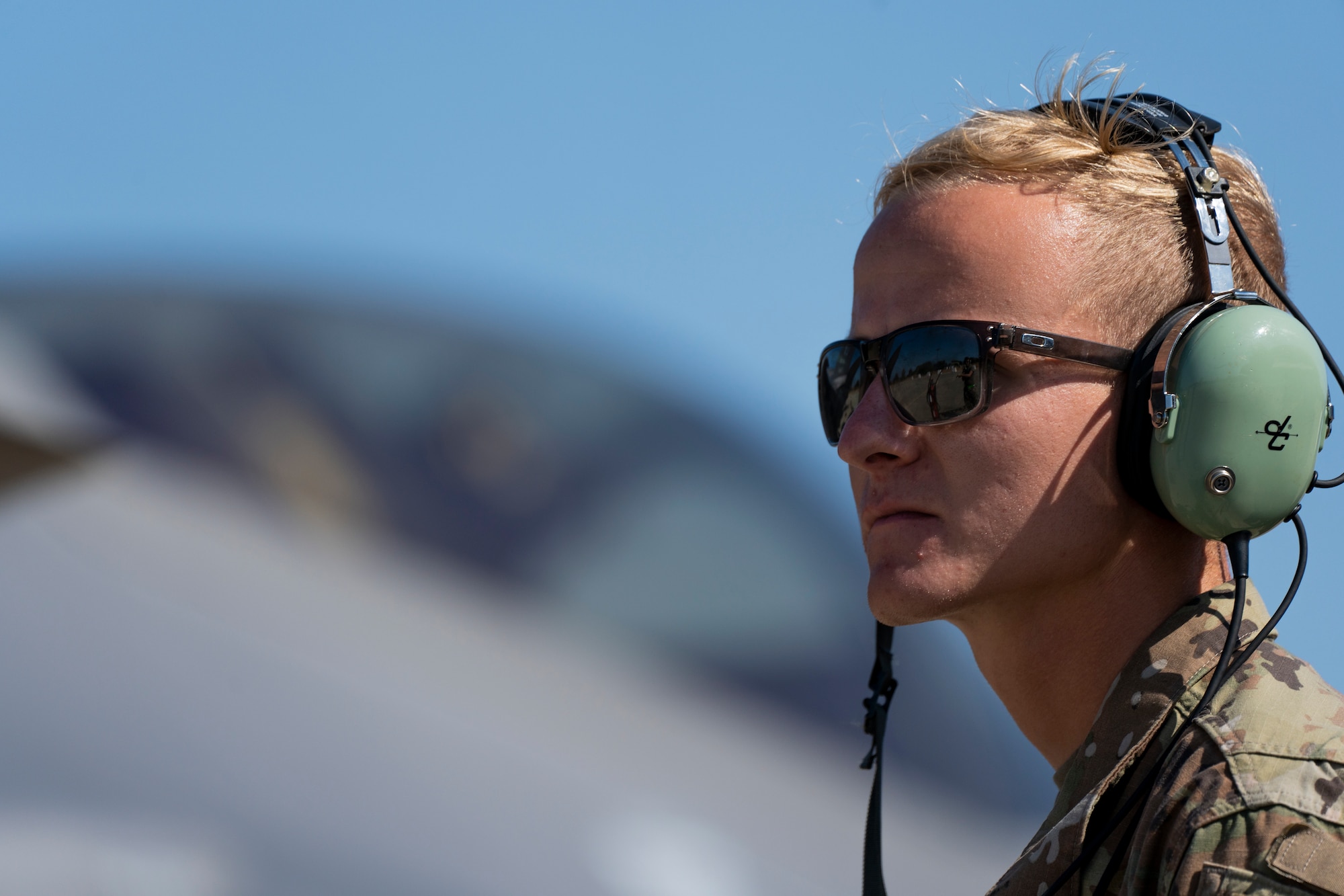 An Airman wearing sunglasses stands in front of a fighter jet