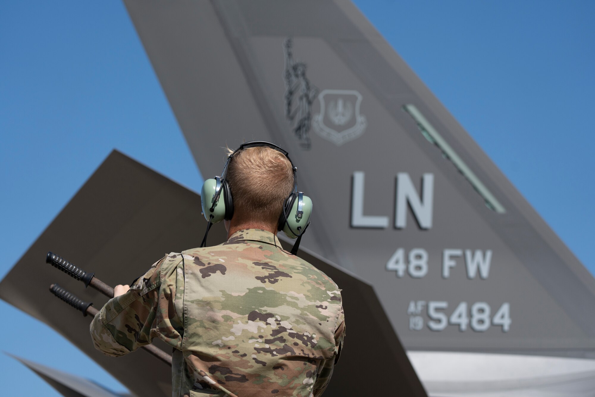 An Airman stands in front of a fighter jet