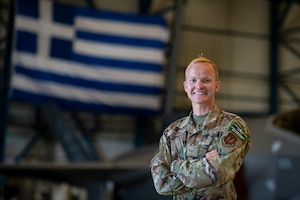 An Airman standing in front of a jet and the Greek flag