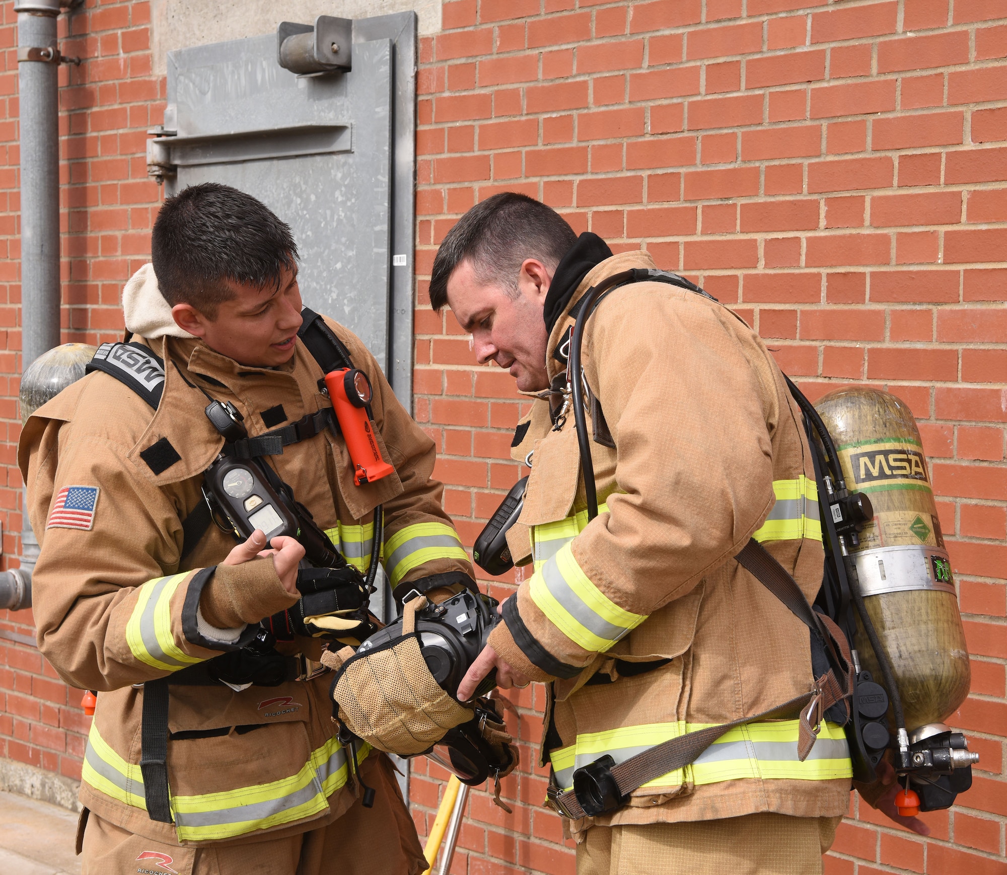 U.S. Air Force Col. Gene Jacobus, 100th Air Refueling Wing commander, right, listens as Staff Sgt. Eric Gonzalez, 100th Civil Engineer Squadron Fire Department lead firefighter, helps do a final check on his face mask as they prepare to enter the live-fire training facility at Royal Air Force Mildenhall, England, July 28, 2022.  The first-hand experience gave the commander a greater insight as to how much training and preparation the base firefighters undertake on a regular basis to ensure they are prepared for any emergency. (U.S. Air Force photo by Karen Abeyasekere)