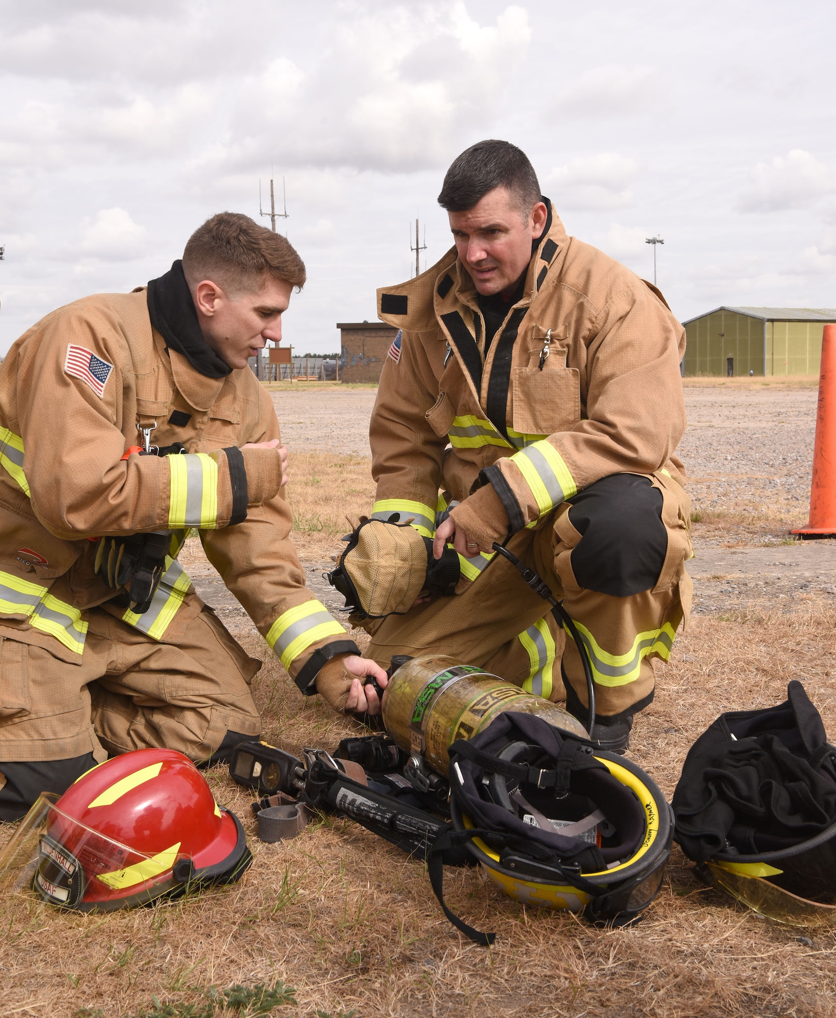 U.S. Air Force Col. Gene Jacobus, 100th Air Refueling Wing commander, right, listens as Airman 1st Class Monty Stingley, 100th Civil Engineer Squadron Fire Department firefighter, explains how to safely operate the breathing apparatus and protective equipment before beginning live-fire training on Royal Air Force Mildenhall, England, July 28, 2022. The first-hand experience gave the commander a greater insight as to how much training and preparation the base firefighters undertake on a regular basis to ensure they are prepared for any emergency. (U.S. Air Force photo by Karen Abeyasekere)