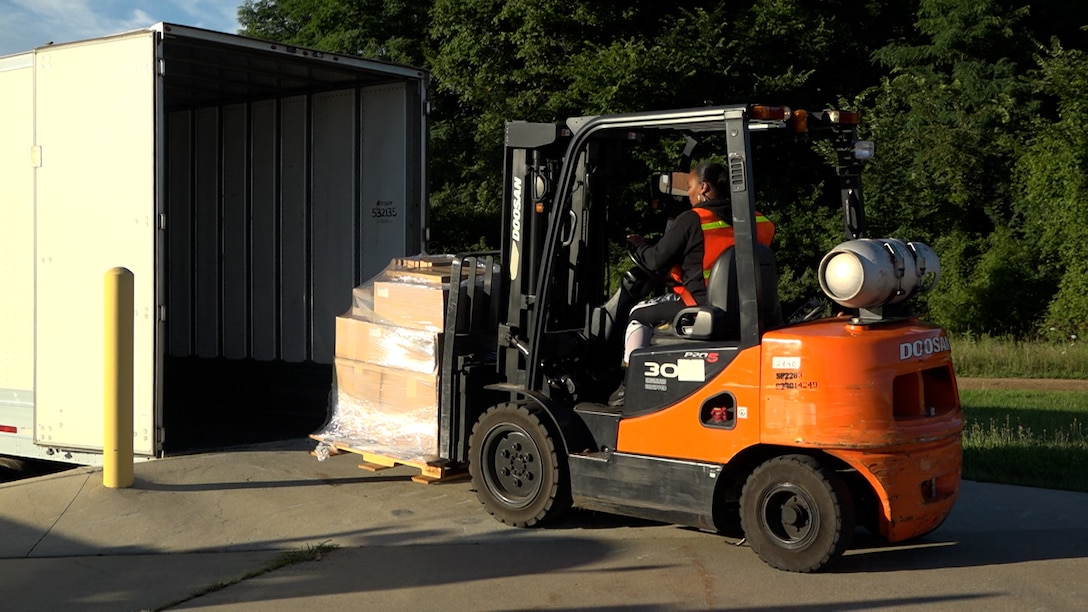 Man unloading boxes from a trailer using forklift