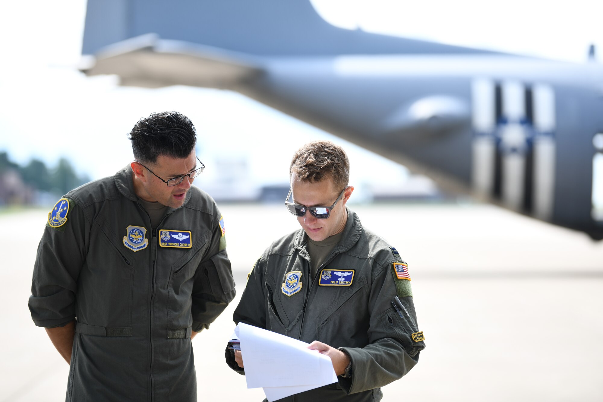Master Sgt. Theodore Clever III and Capt. Philip Savitsky, both members of the Air Mobility Command Test and Evaluation Squadron, review mission details prior to the initial test flight of a prototype modular aerial spray system, July 25, 2022, at Youngstown Air Reserve Station, Ohio.