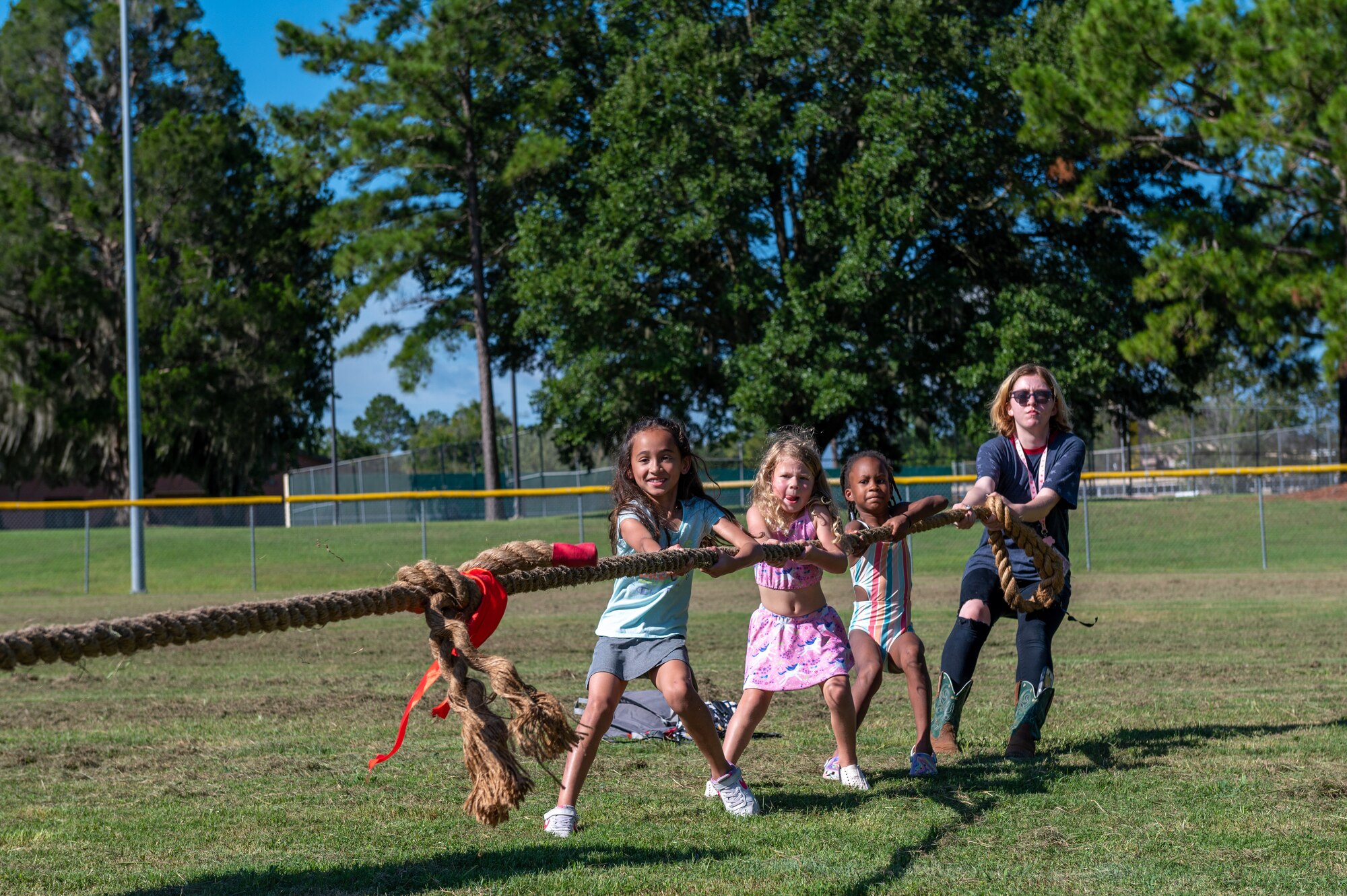 Children pull on a rope during a game of tug-o-war during a Back to School Field Day.