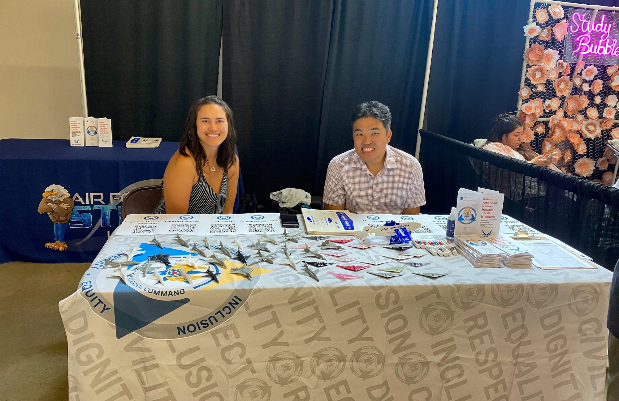 Jenipher Sears and Tony Lau sit behind a information booth table.