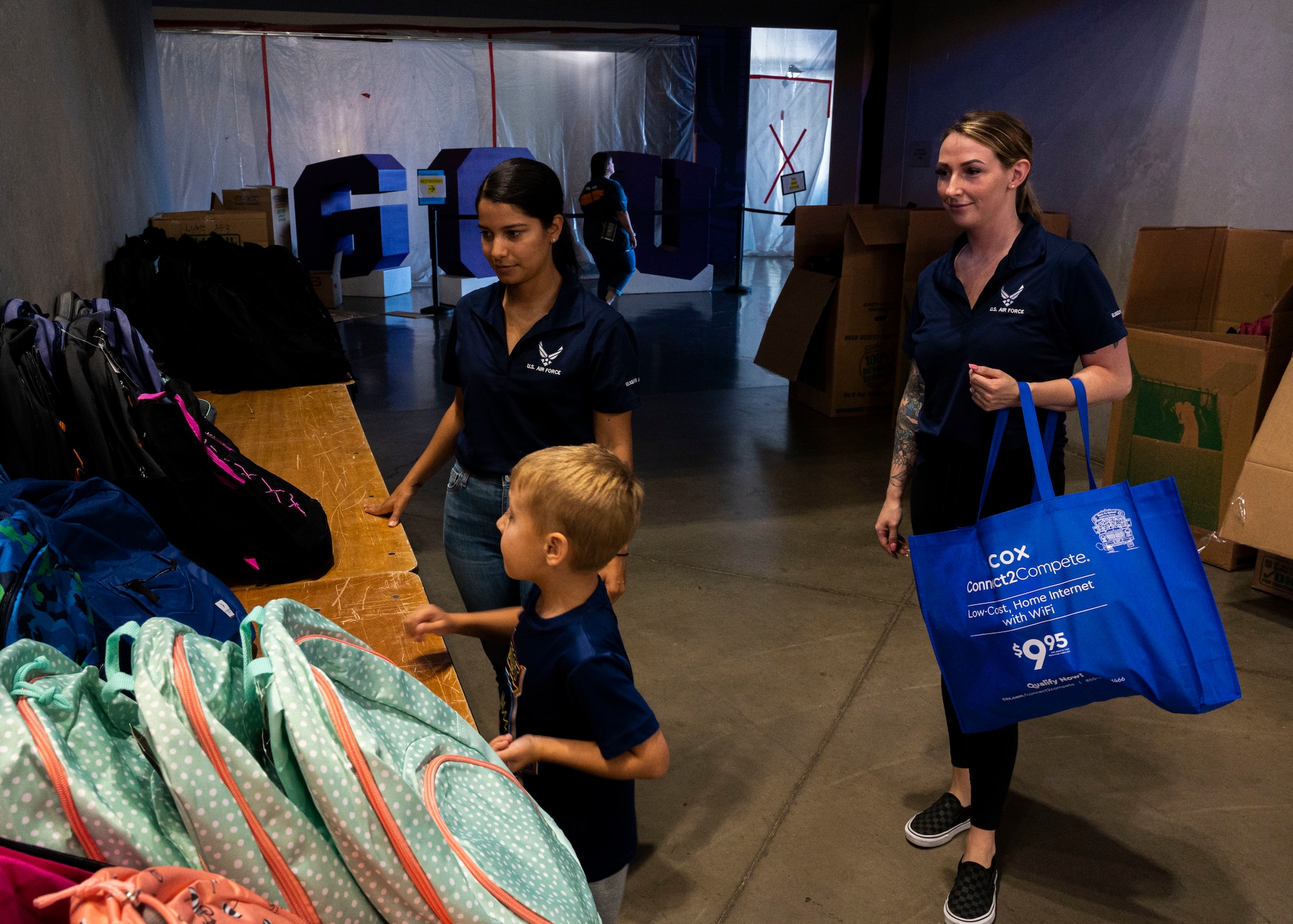 U.S. Air Force Airman 1st Class Alexis Lopez, 56th Fighter Wing religious affairs, and Senior Airman Jamie Samuels, 56th FW religious affairs, help a boy pick out his backpack for school at the Back to School Bash event July 20, 2022, at Grand Canyon University, Phoenix, Arizona.