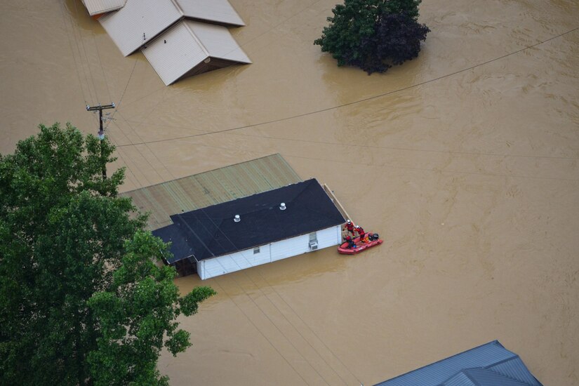 A raft sits in waters by a flooded building.