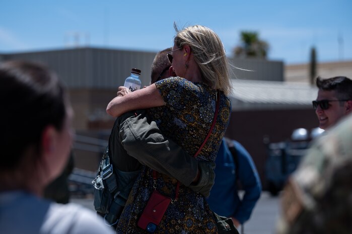 Lt. Col. Kevin "Mongo" Jens assigned to the 59th Test and Evaluation Squadron, 53d Wing, Eglin Air Force Base, Florida, hugs his wife after completing over four thousand flight hours as an F-16 pilot at Nellis Air Force Base, Nevada, July 8, 2022. This is a feat few pilots have been able to accomplish in the Air Force's 75-year history. (U.S. Air Force photo by Airman 1st Class Josey Blades)