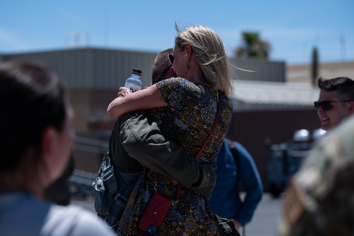 Lt. Col. Kevin "Mongo" Jens assigned to the 59th Test and Evaluation Squadron, 53d Wing, Eglin Air Force Base, Florida, hugs his wife after completing over four thousand flight hours as an F-16 pilot at Nellis Air Force Base, Nevada, July 8, 2022. This is a feat few pilots have been able to accomplish in the Air Force's 75-year history. (U.S. Air Force photo by Airman 1st Class Josey Blades)