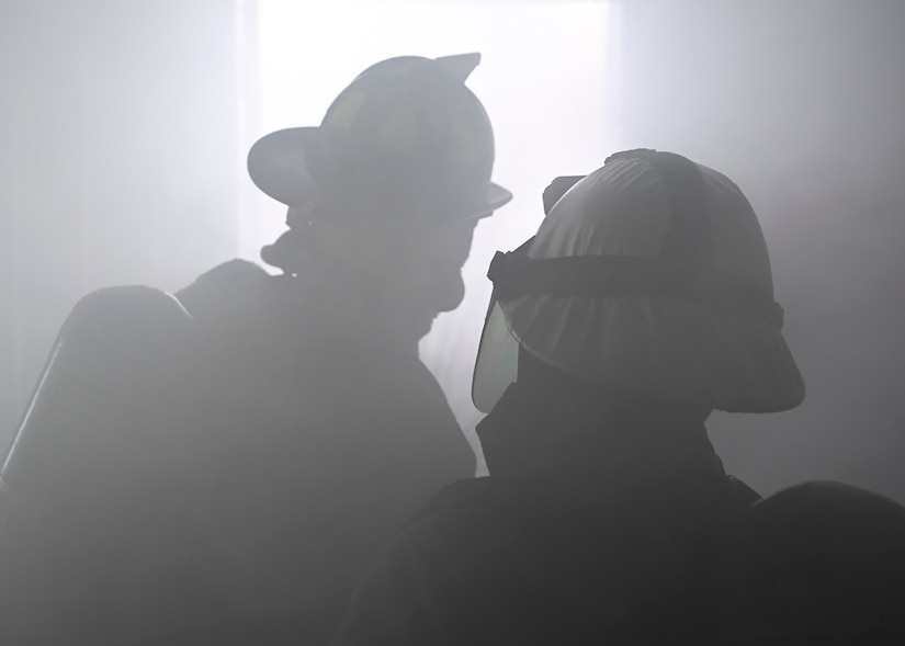 Two cadets clear smoke from a simulated structure fire during the 2022 Fire Explorer Program at Joint Base Andrews, Md., July 30, 2022.