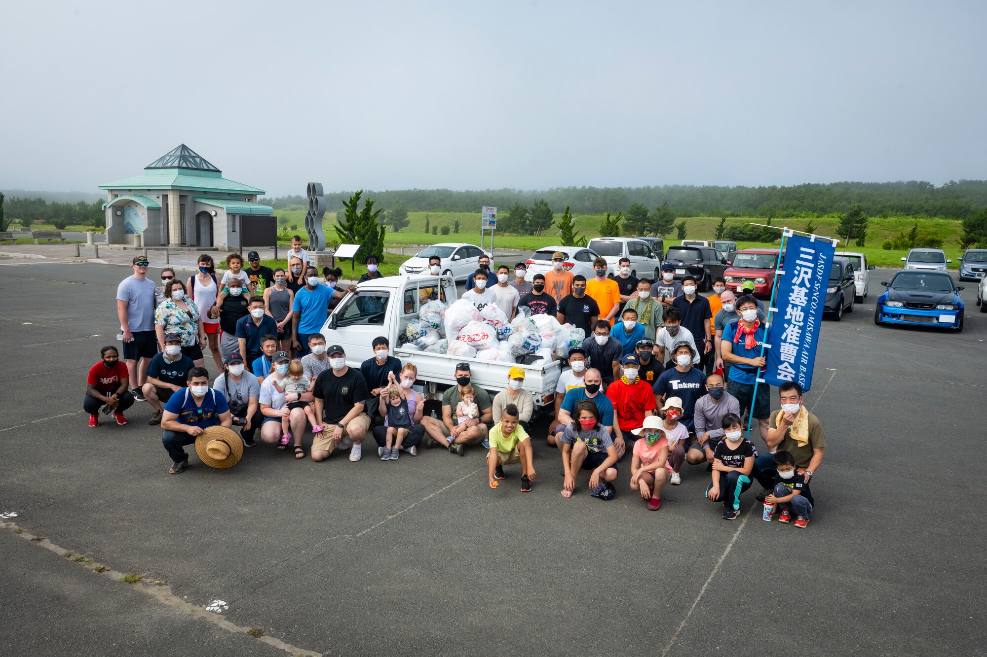People pose around a truck filled with garbage bags.