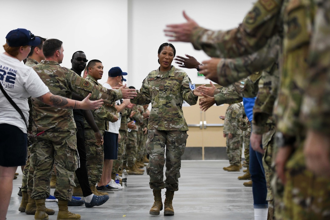 An airman walks and gives high fives to others on either side of the aisle.