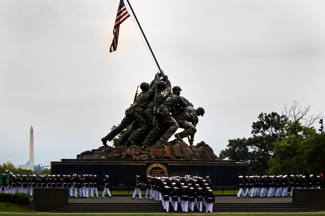 The Washington Monument is seen in the distance as Marines in dress uniform march past the Marine Corps War Memorial.