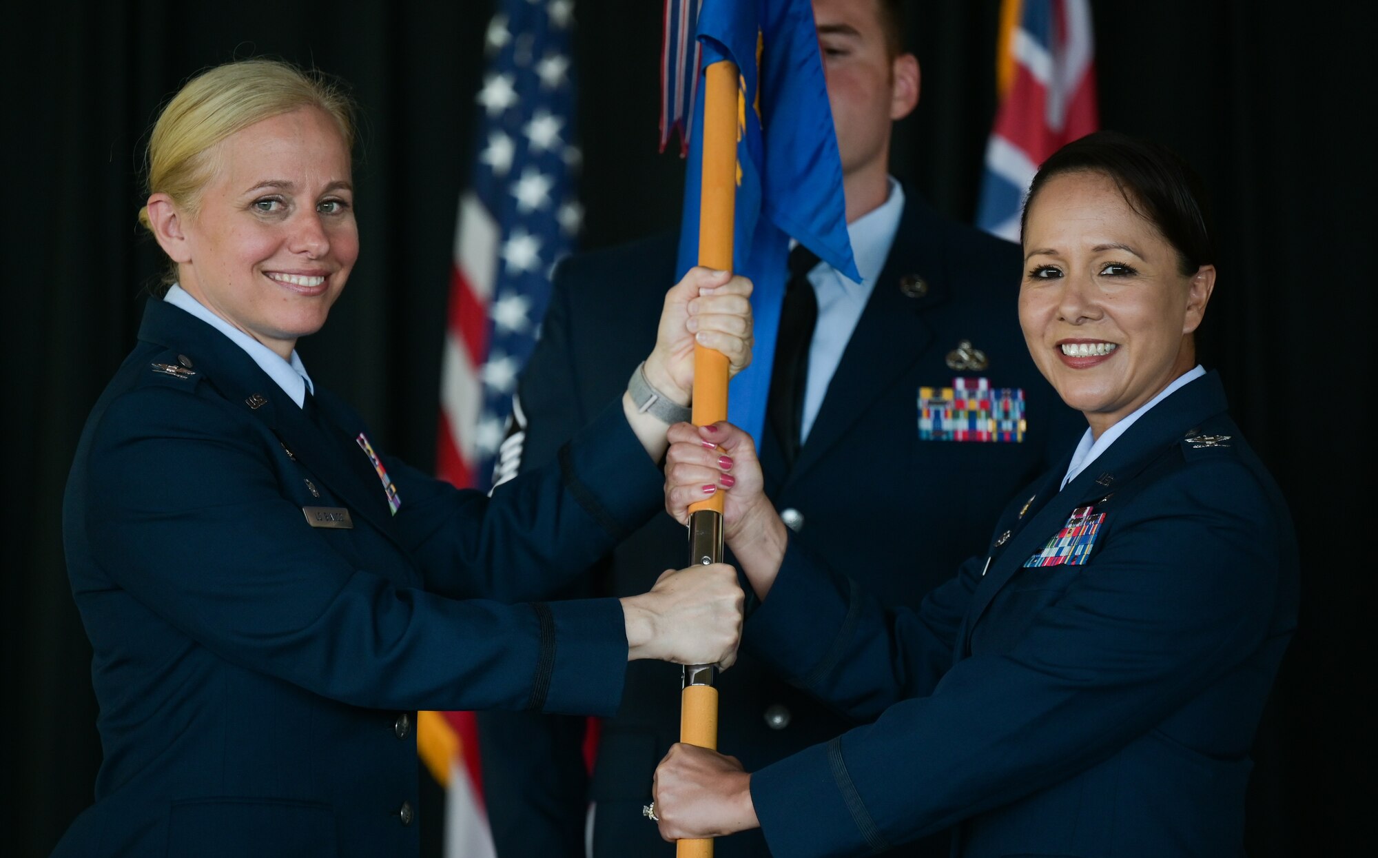 Col. Michele Lo Bianco, 15th Wing commander, hands the guidon to Col. Stella Garcia, 15th Medical Group incoming commander, during a change of command ceremony at Joint Base Pearl Harbor-Hickam, Hawaii, Aug. 1, 2022. During the ceremony, a guidon is passed from the former commander to the new commander, representing the transfer of responsibility. (U.S. Air Force photo by Staff Sgt. Alan Ricker)