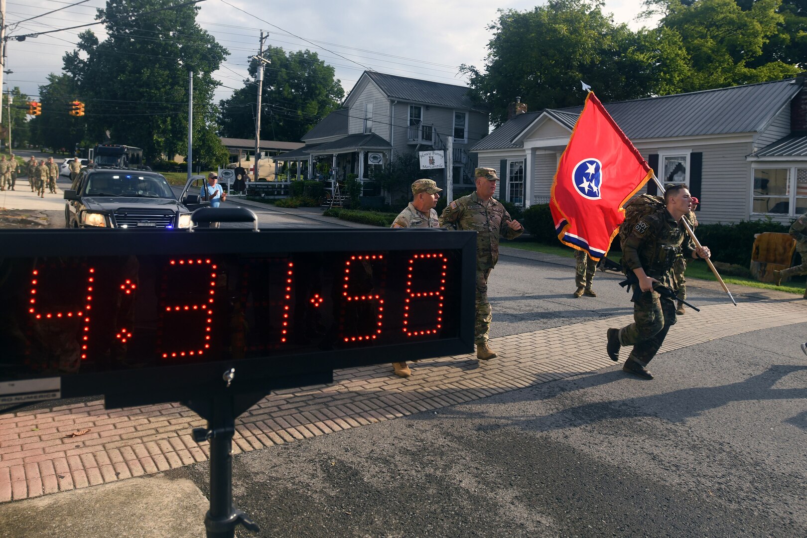 Spc. Grayson Vaughn, a military policeman with the Tennessee Army National Guard’s 252nd Military Police Company, 117th Military Police Battalion, 194th Engineer Brigade, crosses a finish line holding his state’s flag after completing a 16-mile ruck march – the last event of the 2022 Army National Guard Best Warrior Competition, July 29, 2022, in Lynchburg, Tennessee.