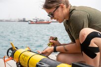 HONOLULU (July 14, 2022) - U.S. Navy Airman Trinity Berg, assigned to U.S. Navy Fleet Survey Team, unscrews a compartment on the IVER3-580 Autonomous Underwater Vehicle (AUV) to add lead weights allowing the AUV to dive in salt water. Aerographer’s Mates from U.S. Navy Fleet Survey Team utilize an IVER3-580 Autonomous Underwater Vehicle to scan the ocean floor for hazards. This is part of a Humanitarian Assistance Disaster Response (HADR) scenario to safely reopen a port following a typhoon. Unmanned and remotely operated vessels extend the capability of interconnected manned platform sensors to enhance the warfighting capacity of multinational joint task forces. Unmanned and remotely operated vessels extend the capability of interconnected manned platform sensors to enhance the warfighting capacity of multinational joint task forces. Twenty-six nations, 38 ships, four submarines, more than 170 aircraft and 25,000 personnel are participating in RIMPAC from June 29 to Aug. 4 in and around the Hawaiian Islands and Southern California. The world's largest international maritime exercise, RIMPAC provides a unique training opportunity while fostering and sustaining cooperative relationships among participants critical to ensuring the safety of sea lanes and security on the world's oceans. RIMPAC 2022 is the 28th exercise in the series that began in 1971. (Royal New Zealand Air Force photo by Cpl. Dillon Anderson)