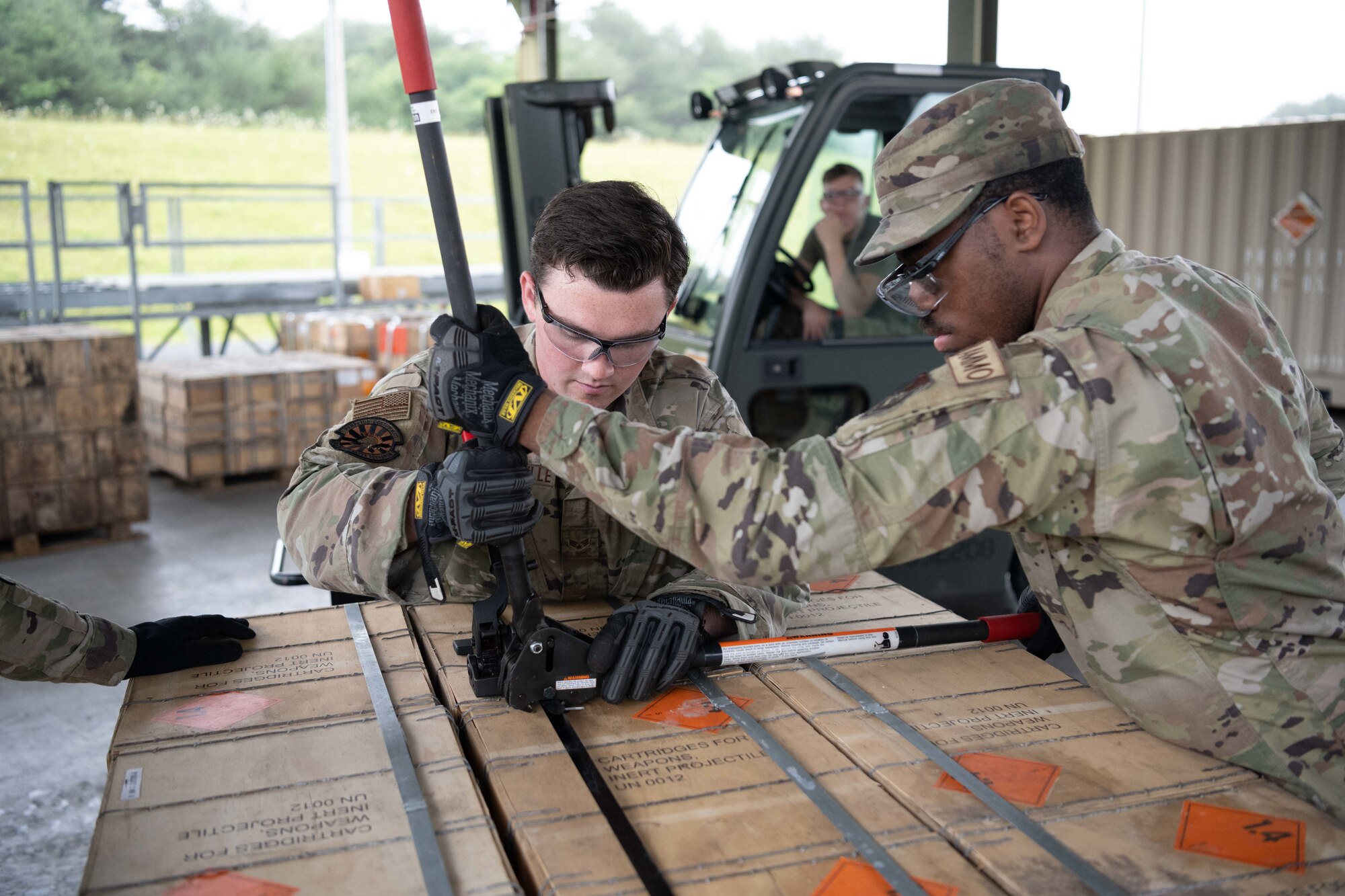 Military members work together to brace a box.